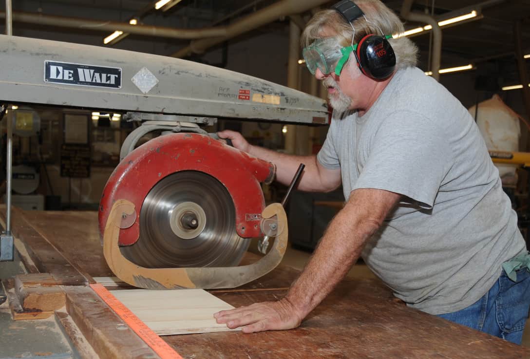 wood shop manager operates a radial arm saw